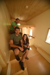 Bob Greel, Kate Ziegler and Anderson Page from Tiny House Crafters LLC, sit on the stairway/storage unit in one of the company’s homes. (Contributed photo)